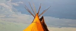 a painting by Russell Nahdee depicts the top of a tipi against a cloudy blue sky